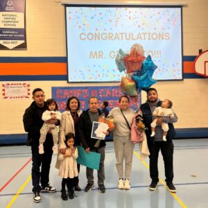 Mr. Alba standing with his family after receiving the District 54 Blue Apple Award